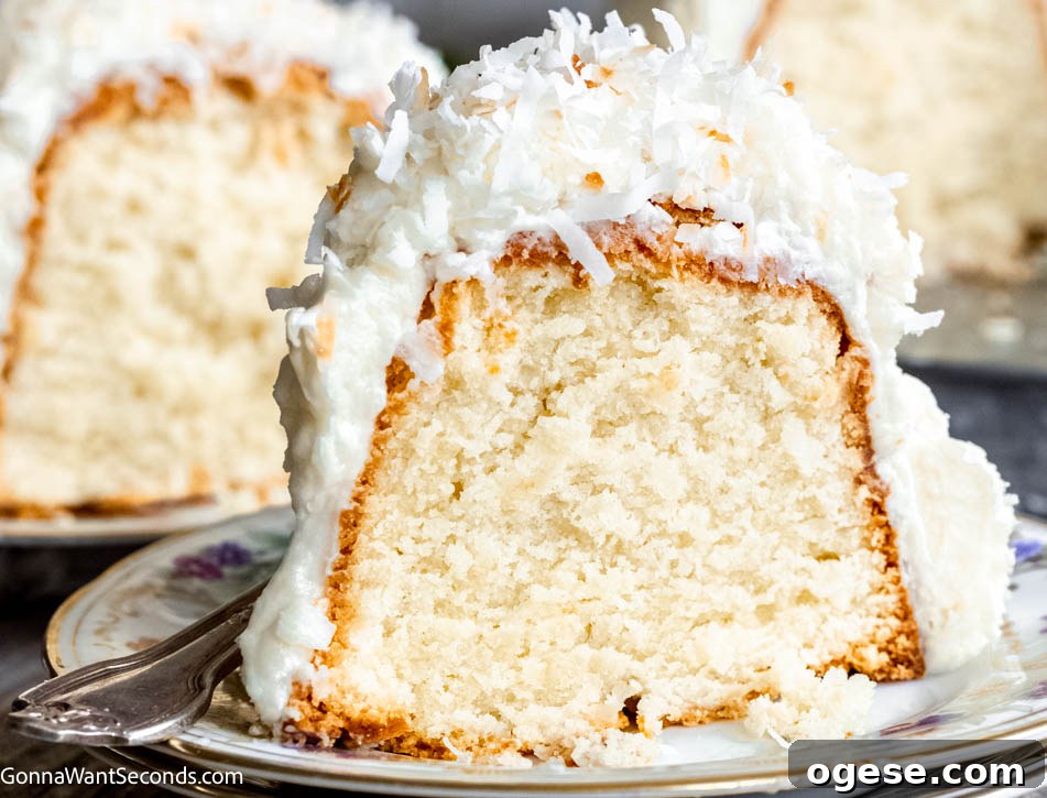 Our Tom Cruise cake features a rich coconut batter, a chewy coconut layer, and cream cheese frosting topped with coconut! Best cake EVER! #tomcruisecake #coconutcake a slice of Tom Cruise Coconut Cake