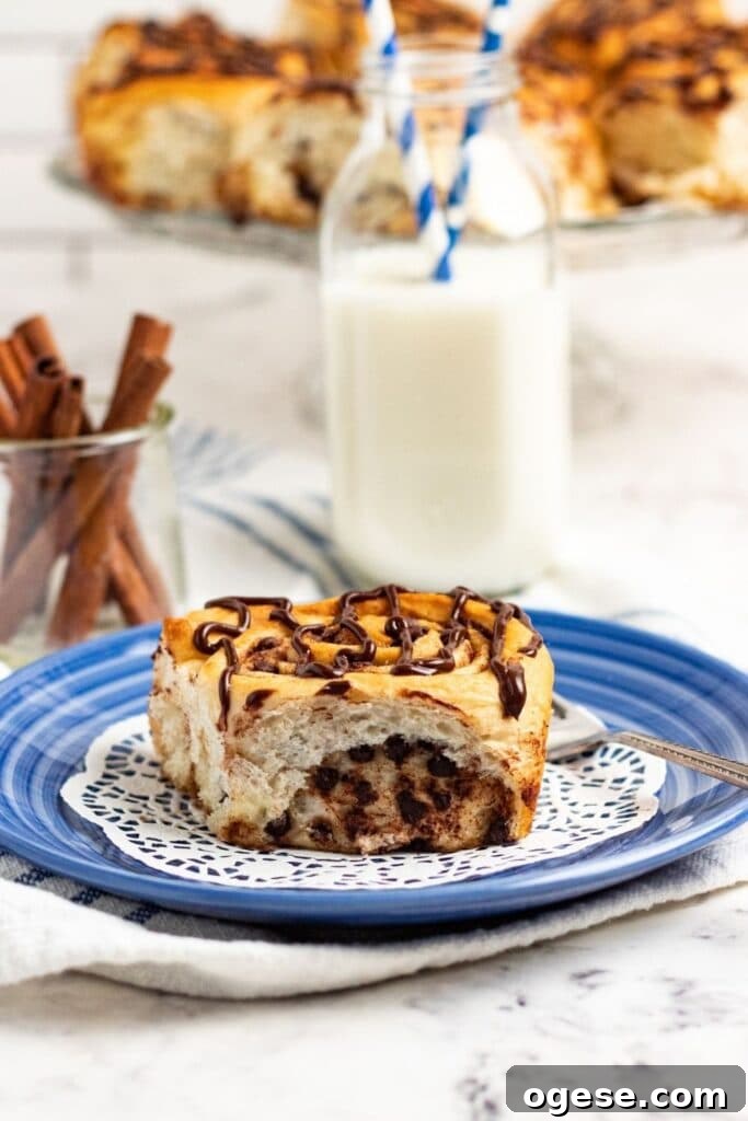 Chocolate Chip Cinnamon Rolls with Rich Chocolate Swirl 5 chocolate drizzled cinnamon roll on plate with milk behind it
