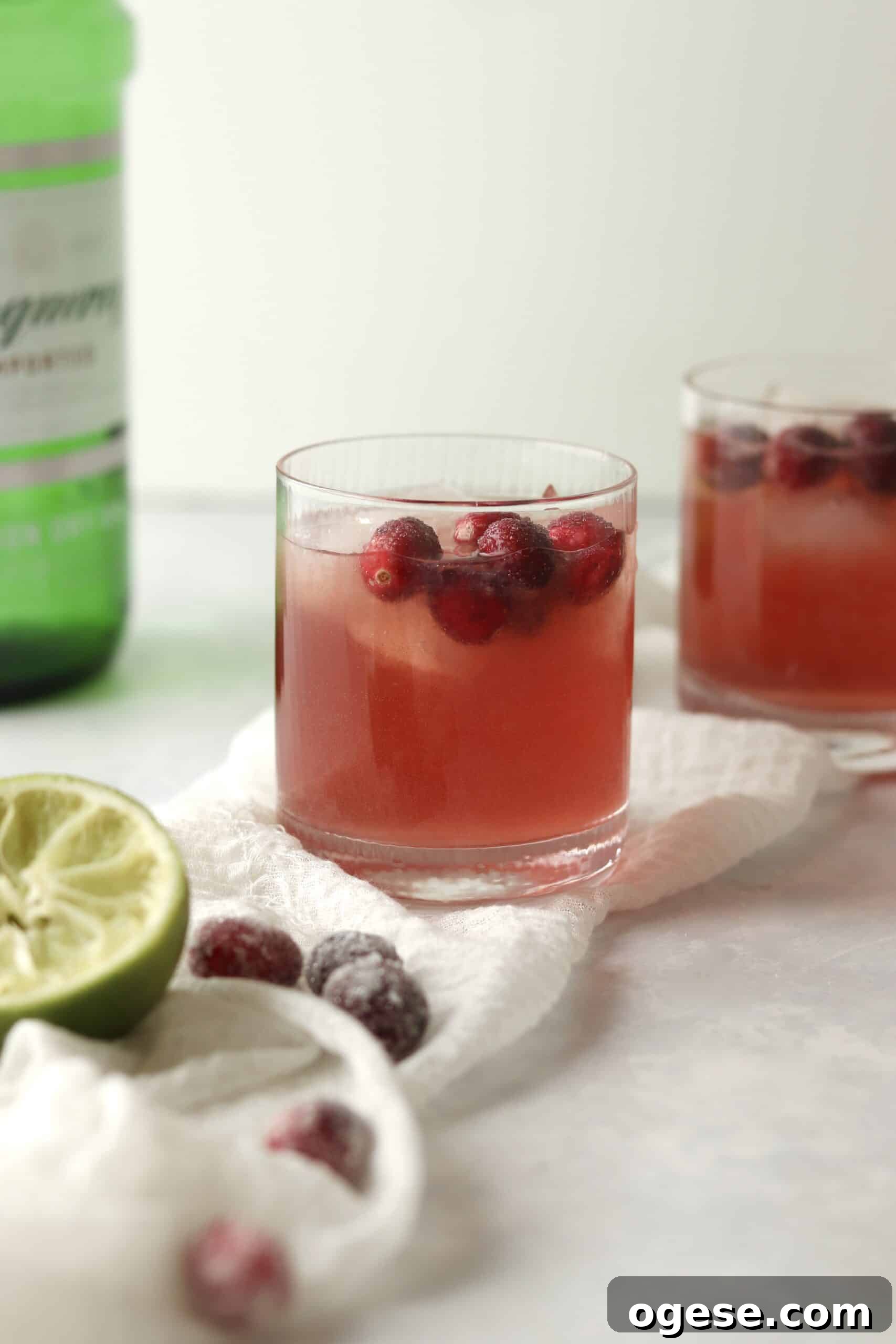 christmas cranberry cocktail with a bottle of gin in the background