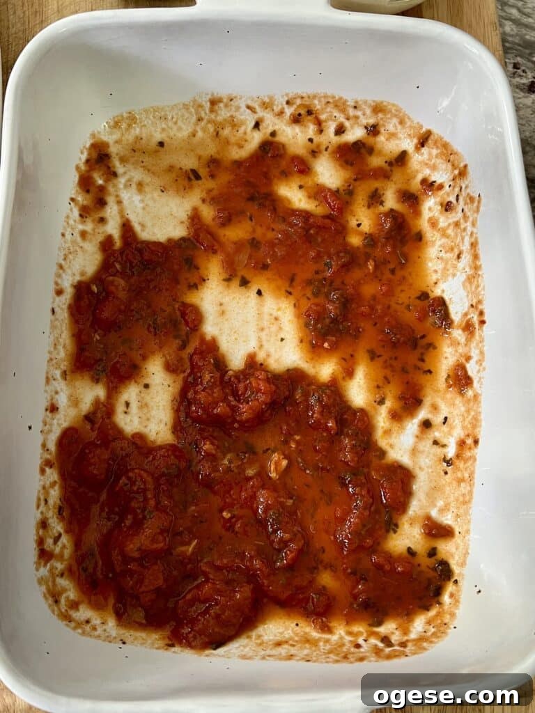 Building the recipe: tomato sauce on bottom of baking dish.