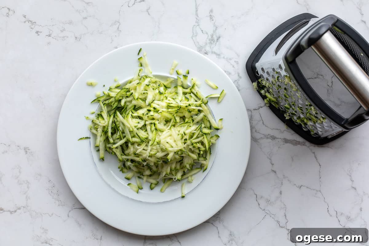 grated zucchini on plate next to grater.