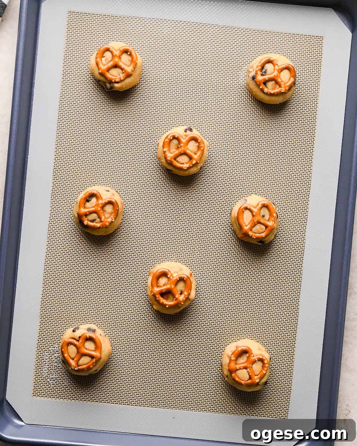 Salted Pretzel Chocolate Chip Cookies: Sweet Meets Crunch 20 8 balls of chocolate chip pretzel cookies dough with pretzel on top on a baking sheet before baking