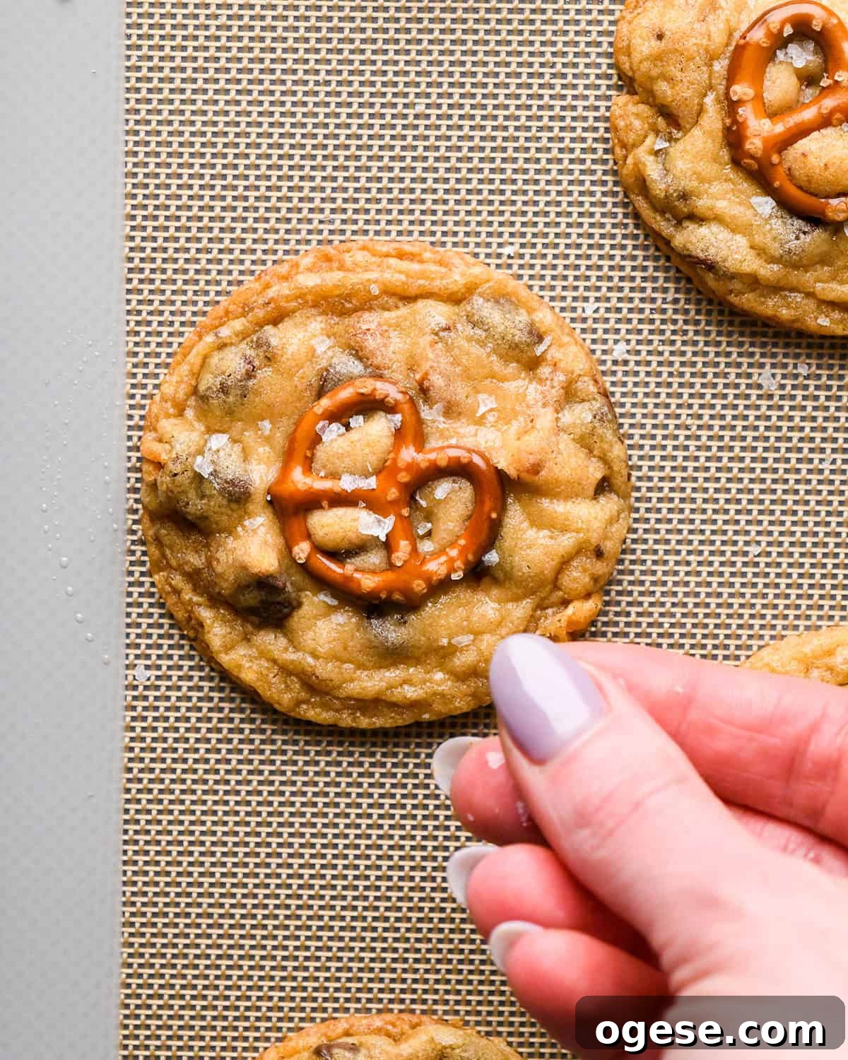 Salted Pretzel Chocolate Chip Cookies: Sweet Meets Crunch 22 a hand sprinkling flaky sea salt on a Pretzel Cookie