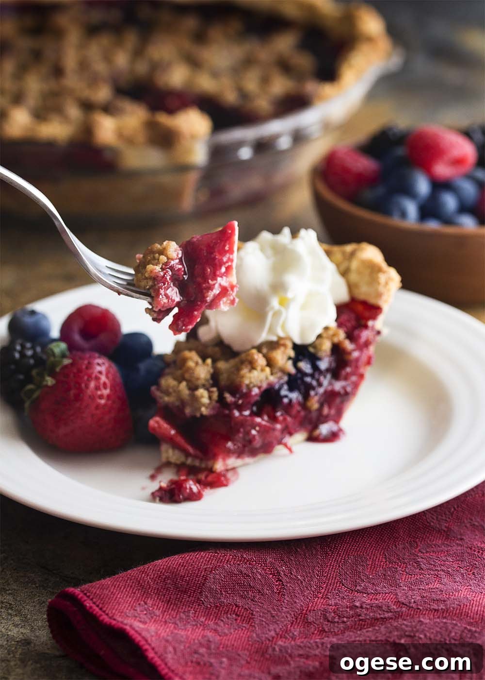 Midsummer mixed berry pie with crumb topping A slice of midsummer mixed berry pie with a crumb topping showing a forkful of the pie.