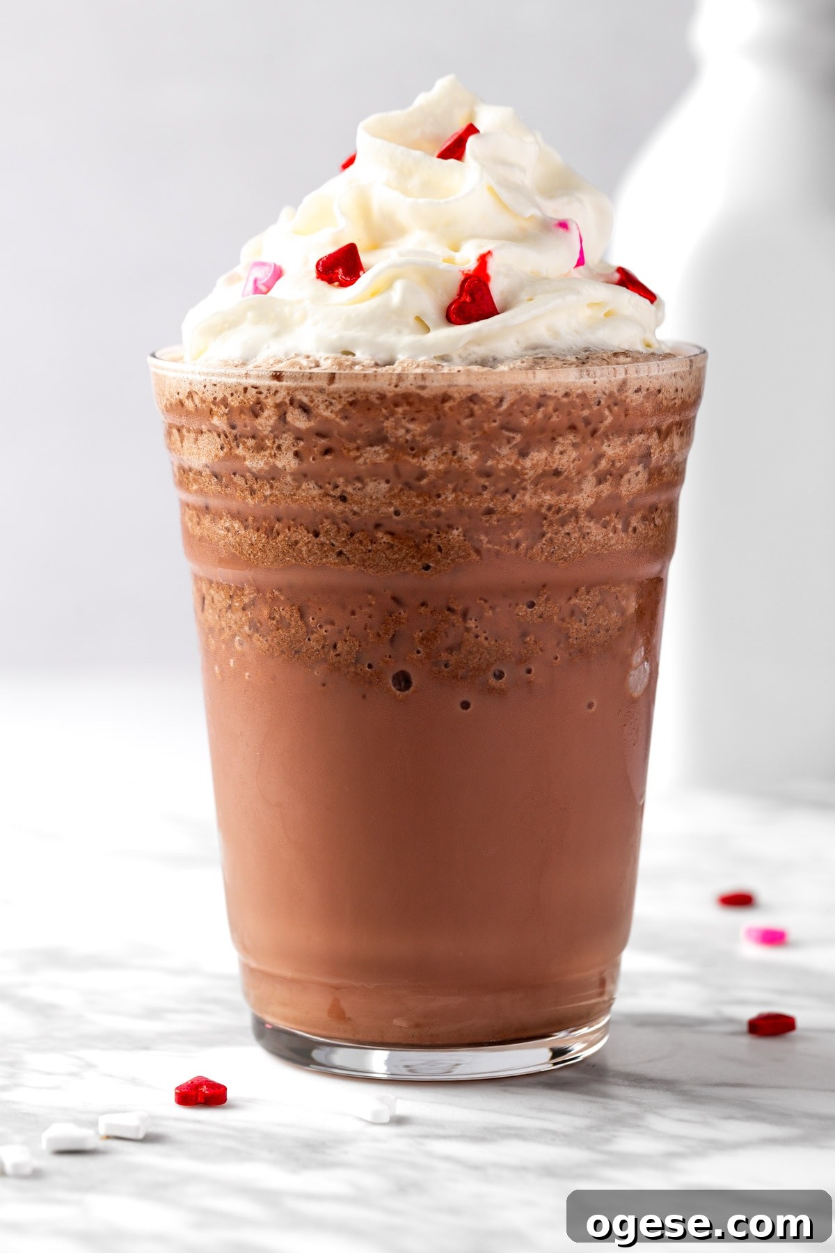 Red Velvet Frappuccino Recipe: Creamy Iced Dessert Drink 8 A red velvet frappuccino topped with whipped cream on white background.