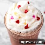 A red velvet frappuccino topped with whipped cream and heart sprinkles.