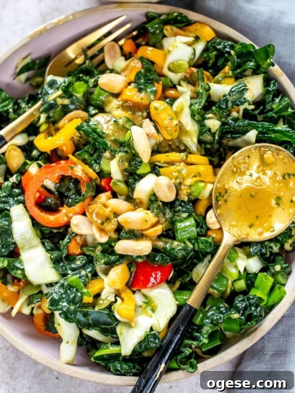 Grey plate with kale and peanuts. Dressing and fork on the side.