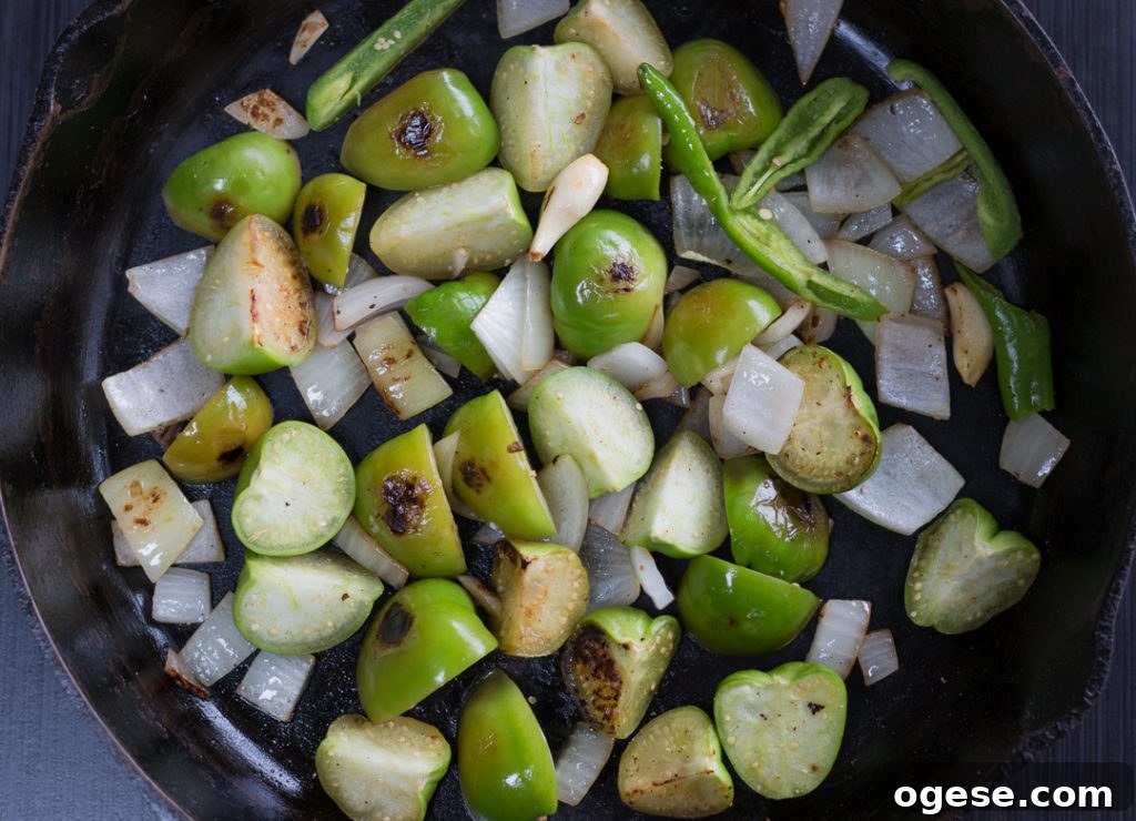 Blistering tomatillos, garlic and onions in a pan