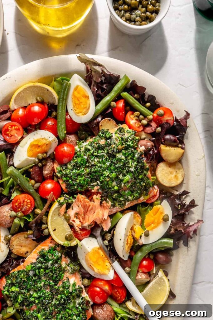 Mediterranean-inspired salmon Niçoise salad with eggs, tomatoes, olives, capers, and mixed greens.