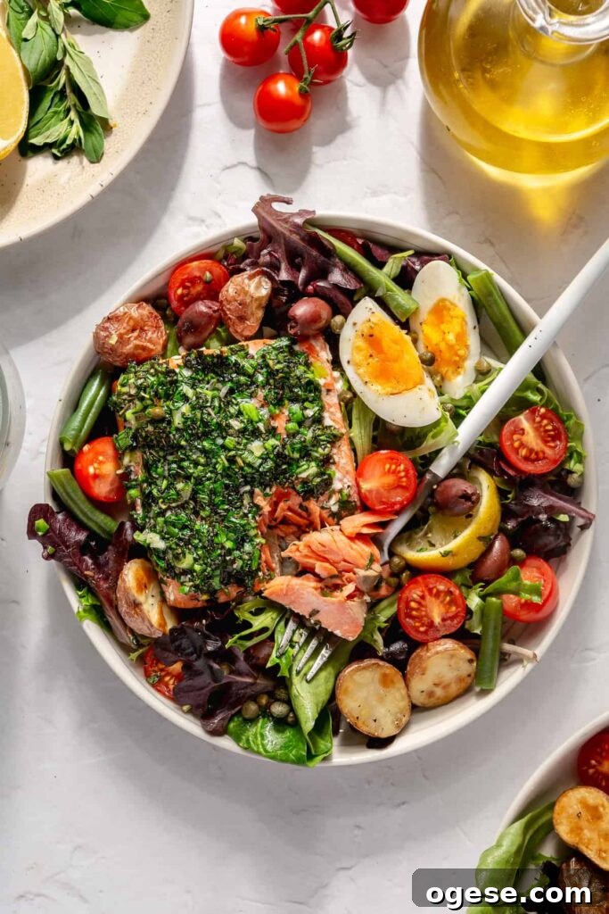 Forkful of healthy salmon Niçoise salad with wild salmon, potatoes, and fresh vegetables.