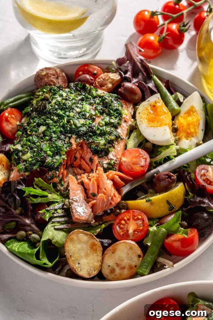 Healthy salmon Niçoise salad served with roasted potatoes, fresh vegetables, hard-boiled eggs, and Dijon dressing.