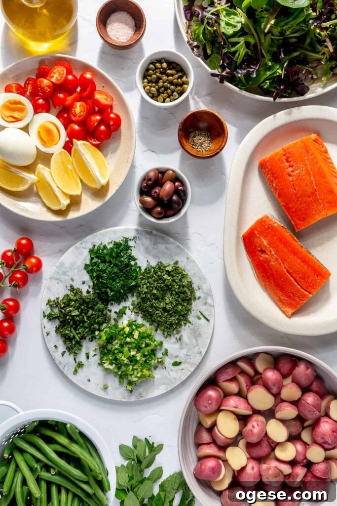 Ingredients for homemade salmon Niçoise salad including wild salmon, potatoes, eggs, green beans, tomatoes, olives, and capers.