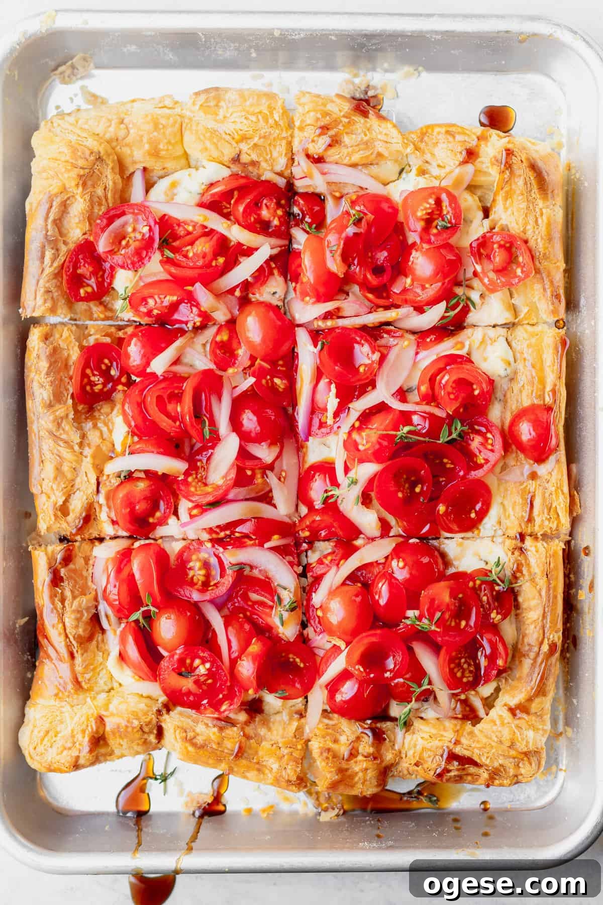 tomato tart on a baking sheet sliced into squares.