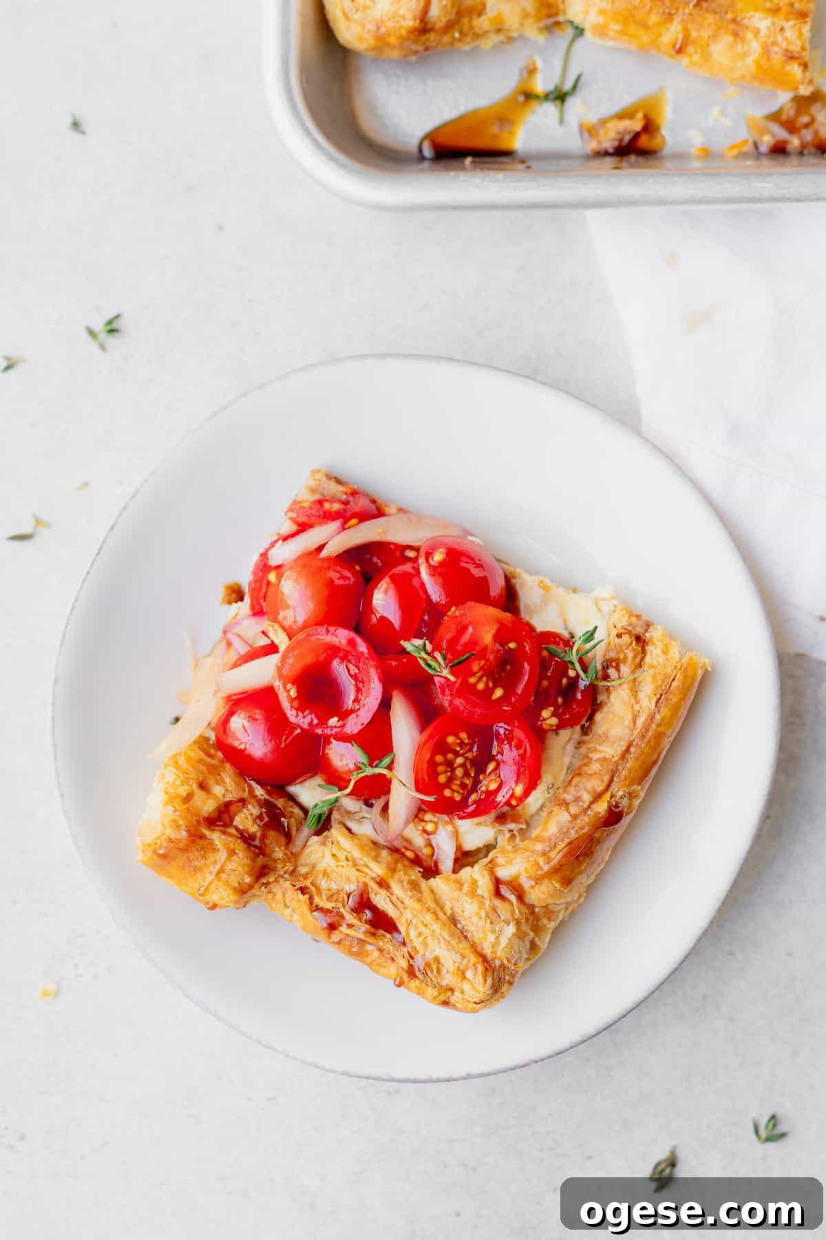 slice of tomato tart on a plate topped with fresh thyme.