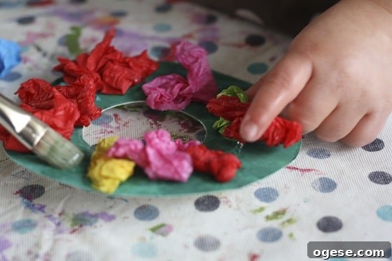 Toddler Christmas Craft: Tissue Paper Wreath 6 gluing tissue paper to cardboard wreath