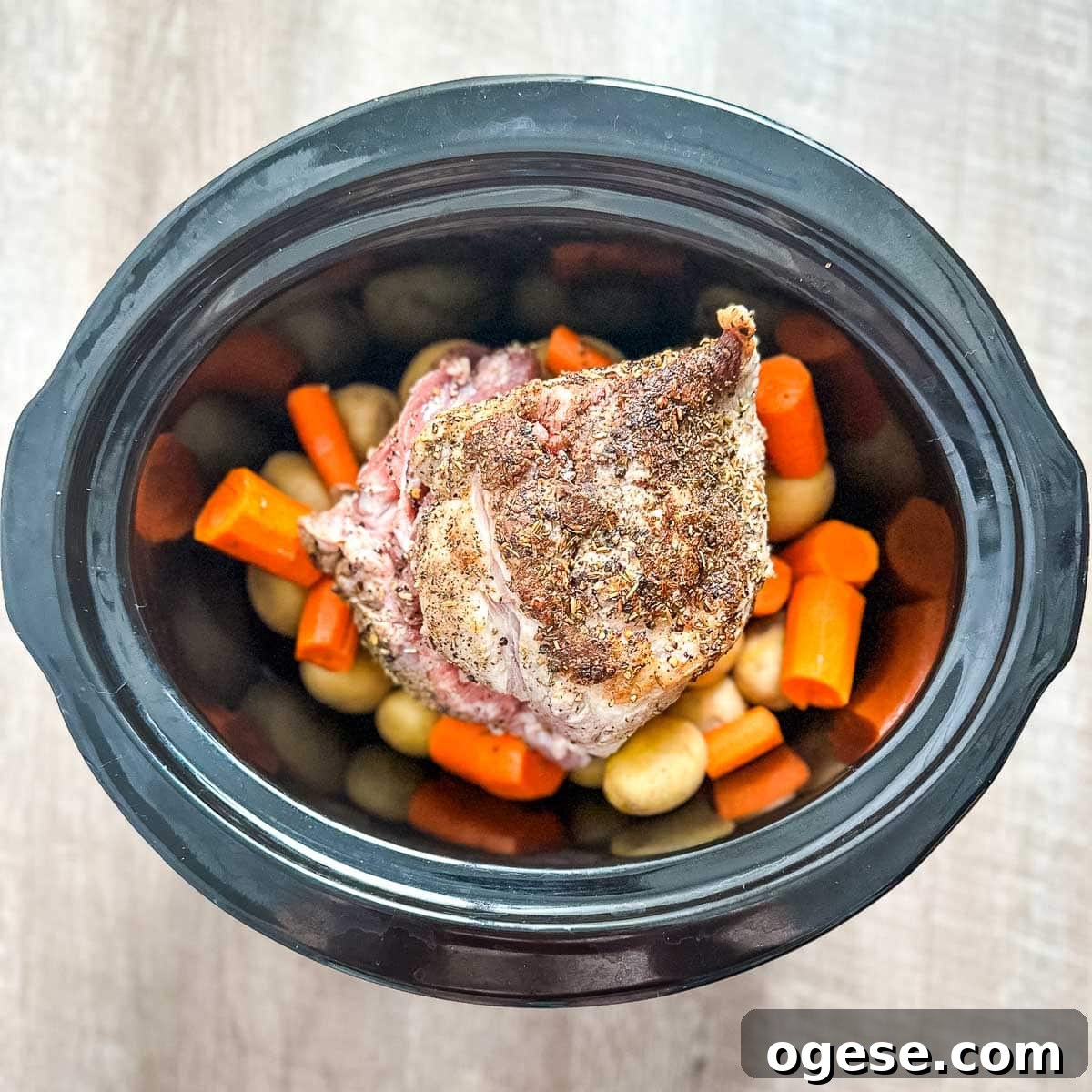 Slow Cooker Italian Pork Roast with Garlic and Herbs 12 A crock pot filled with pork roast, potatoes, and carrots.