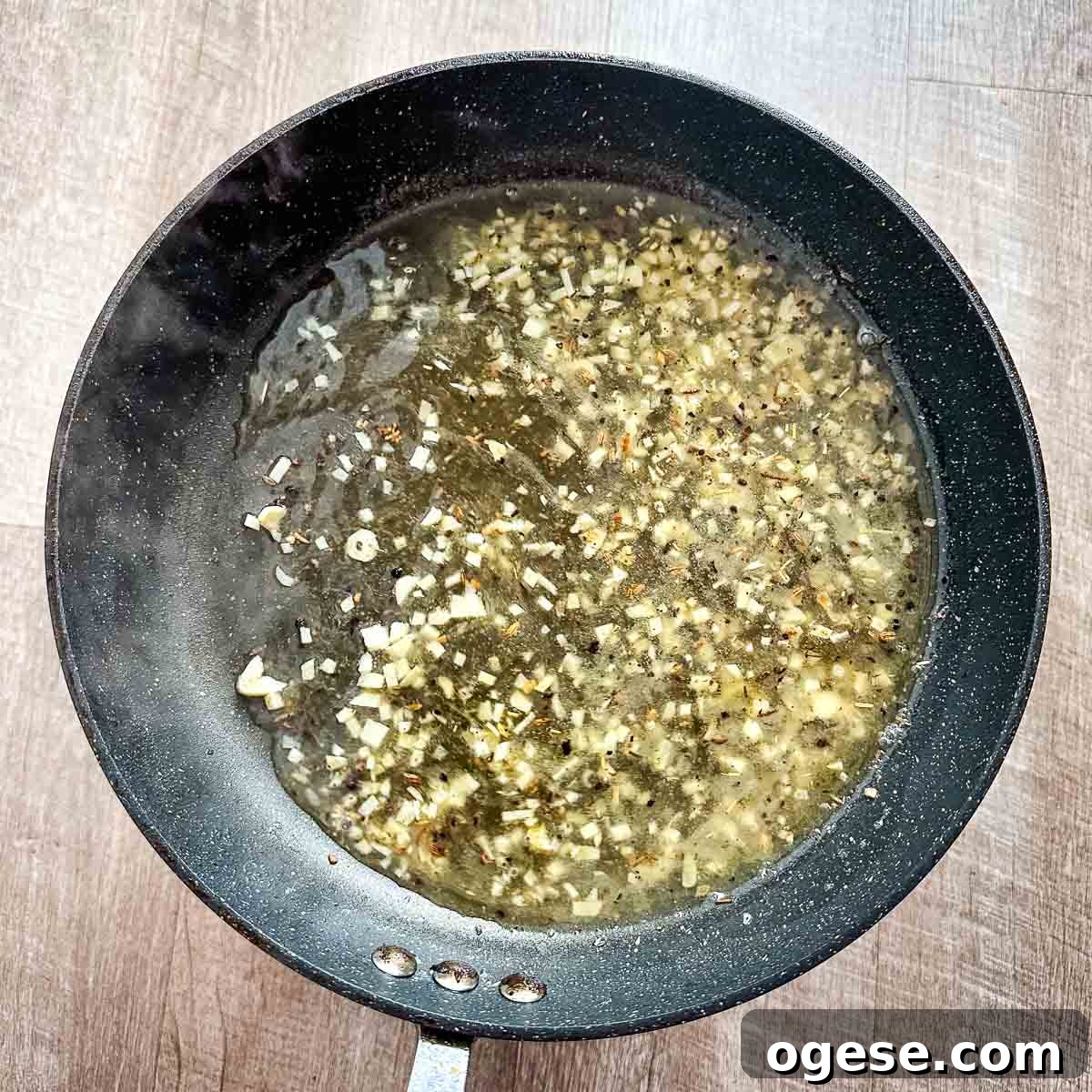 Slow Cooker Italian Pork Roast with Garlic and Herbs 14 A frying pan filled with garlic, white wine, and chicken stock.