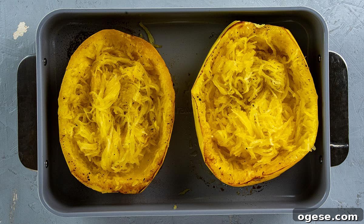 Cheesy Stuffed Spaghetti Squash with Herbs and Parmesan 10 Roasted spaghetti squash halves with inside scooped with a fork.