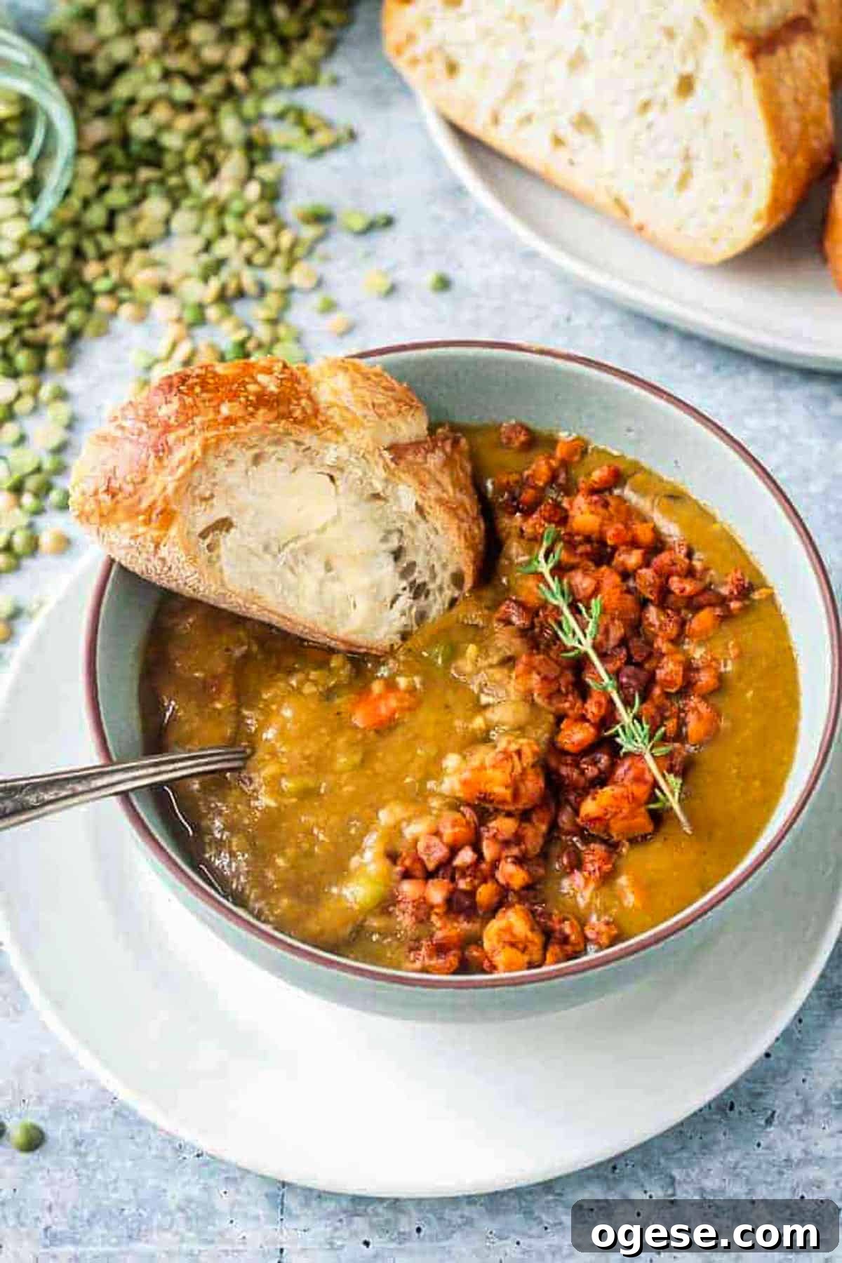 Instant Pot Vegan Split Pea Soup with Smoky Flavor 2 A slice of buttered bread being dunked in a bowl of soup.