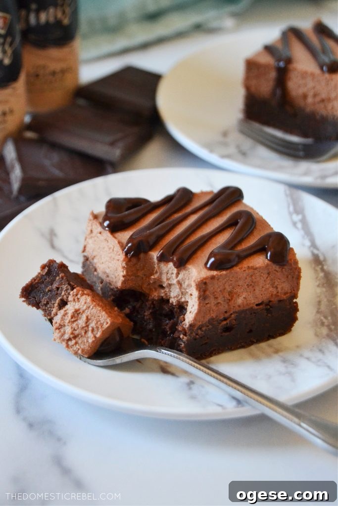 Piece of a Bailey's chocolate mousse brownie on a white plate with a fork
