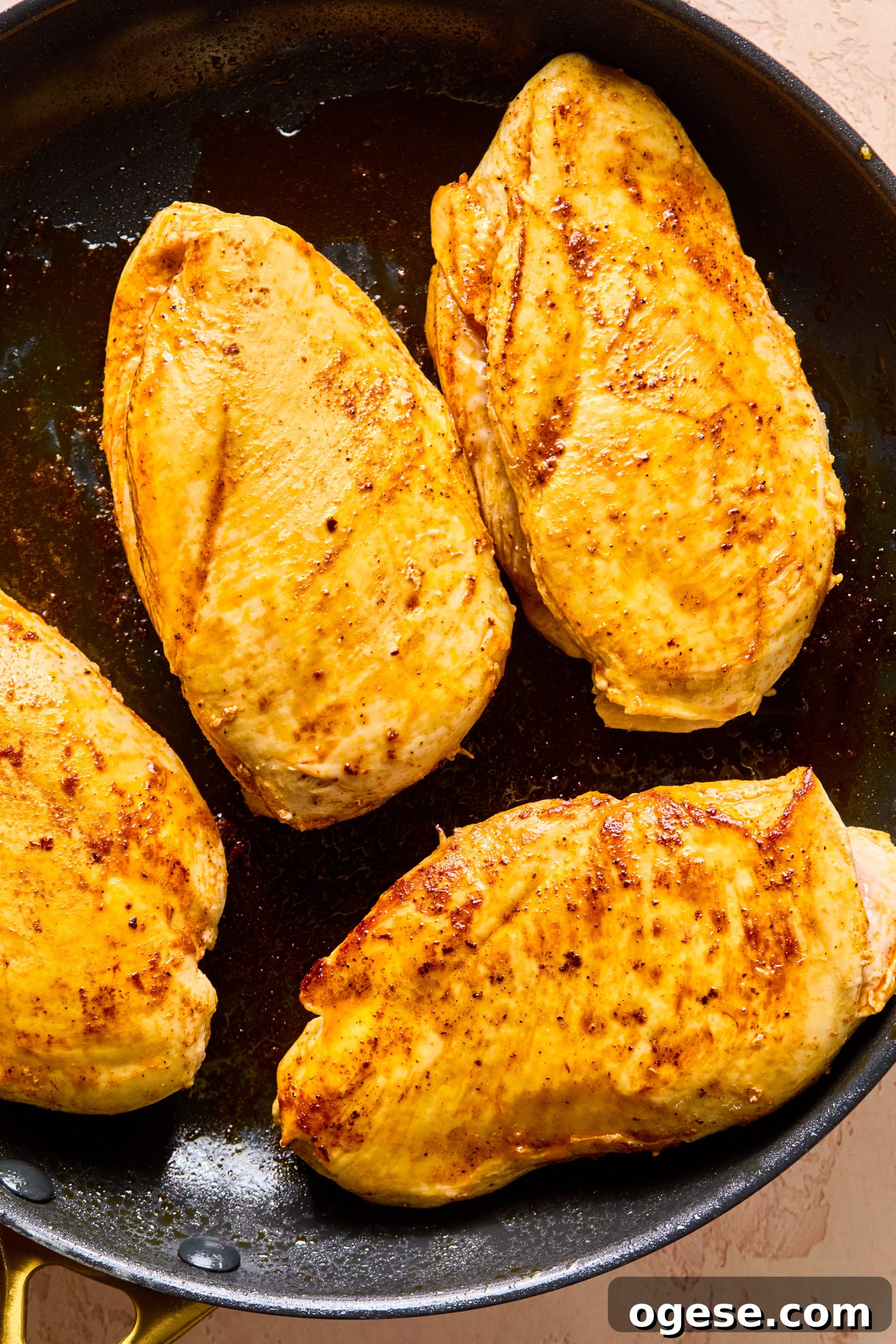 Seasoned chicken breasts seared in a large skillet