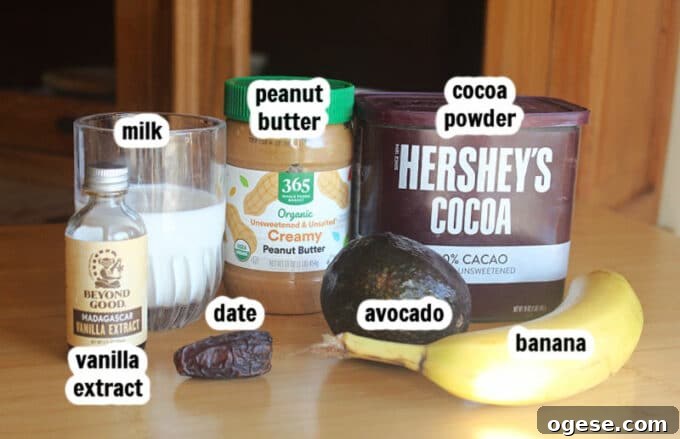 Creamy Chocolate Peanut Butter Banana Smoothie 3 Ingredients on a table, including cocoa, peanut butter, milk, and banana.
