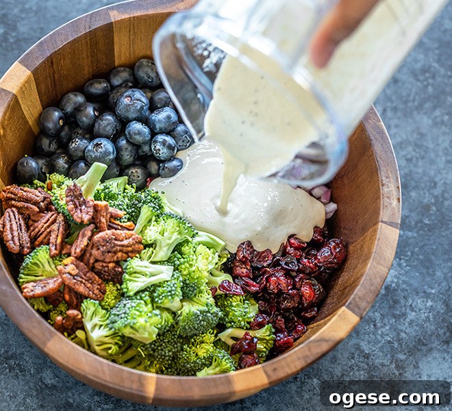 Vegan Broccoli & Blueberry Salad with Lemon Vinaigrette 6 dressing being poured over a bowl of vegan broccoli salad