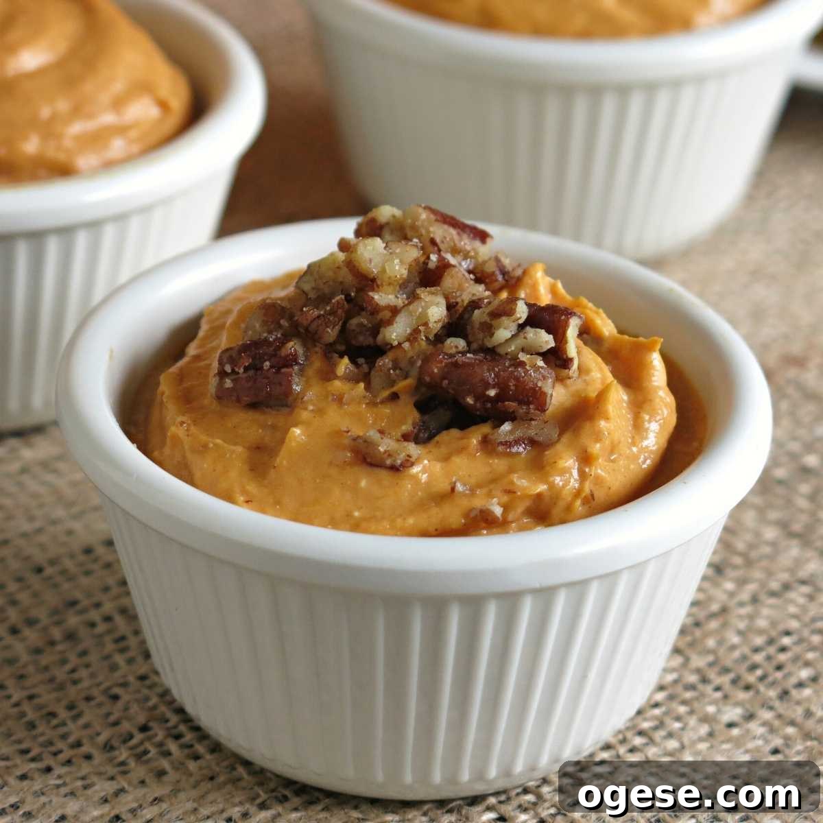Creamy Pumpkin and Cream Cheese Dip for Fall Parties 2 Pumpkin cream cheese dip in a serving cup topped with candied pecans.