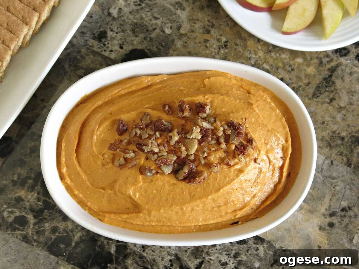Creamy Pumpkin and Cream Cheese Dip for Fall Parties 5 Large serving dish with pumpkin cheesecake dip topped with candied pecans.