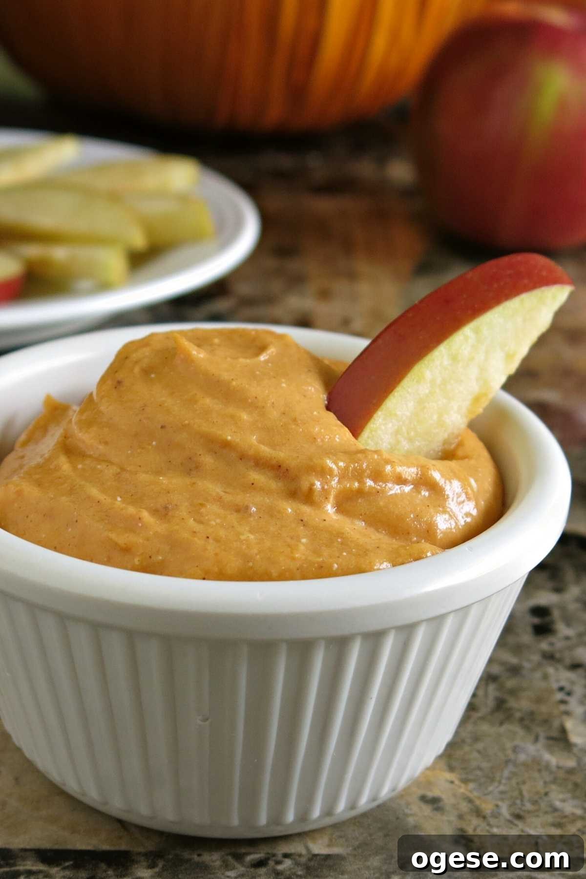 Creamy Pumpkin and Cream Cheese Dip for Fall Parties 6 Pumpkin Cream Cheese Dip in serving cup with apple wedge.