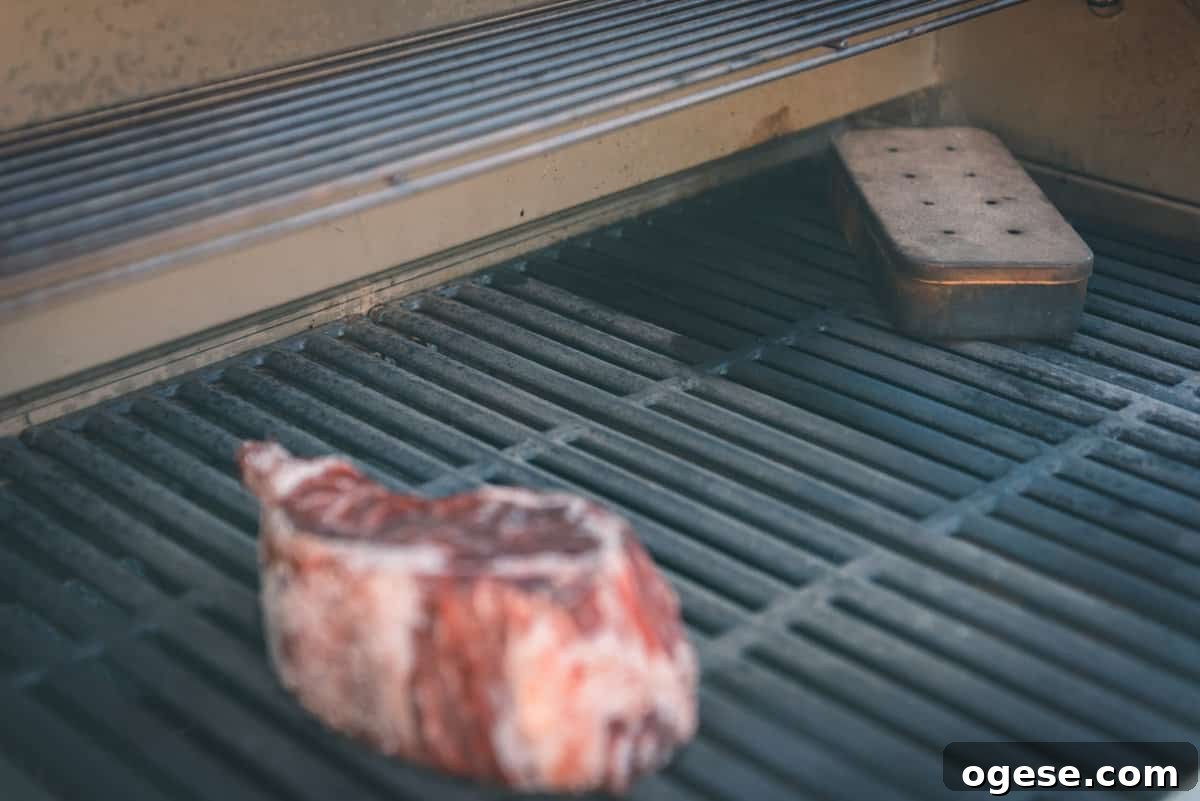 Smoket box on grill grates with a steak on the grill. 