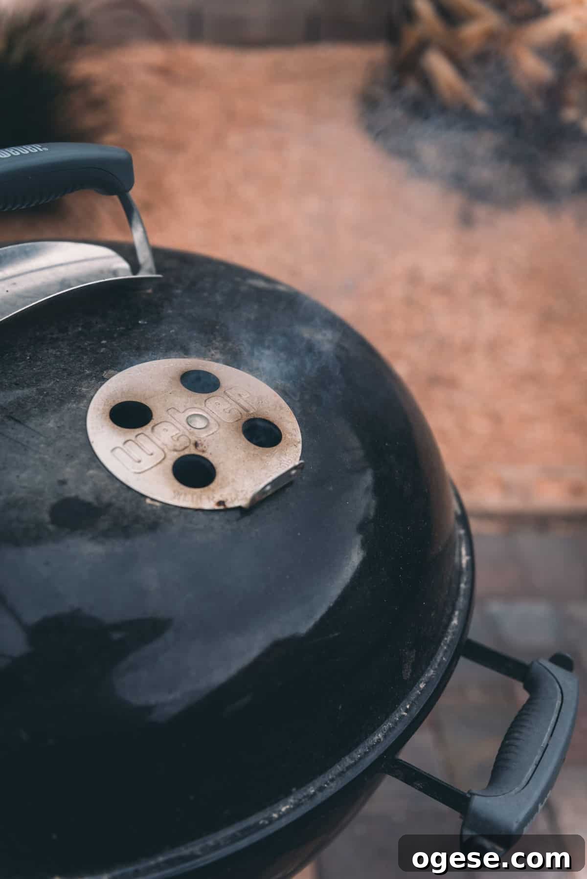 Weber grill with smoke coming out of the air vents. 