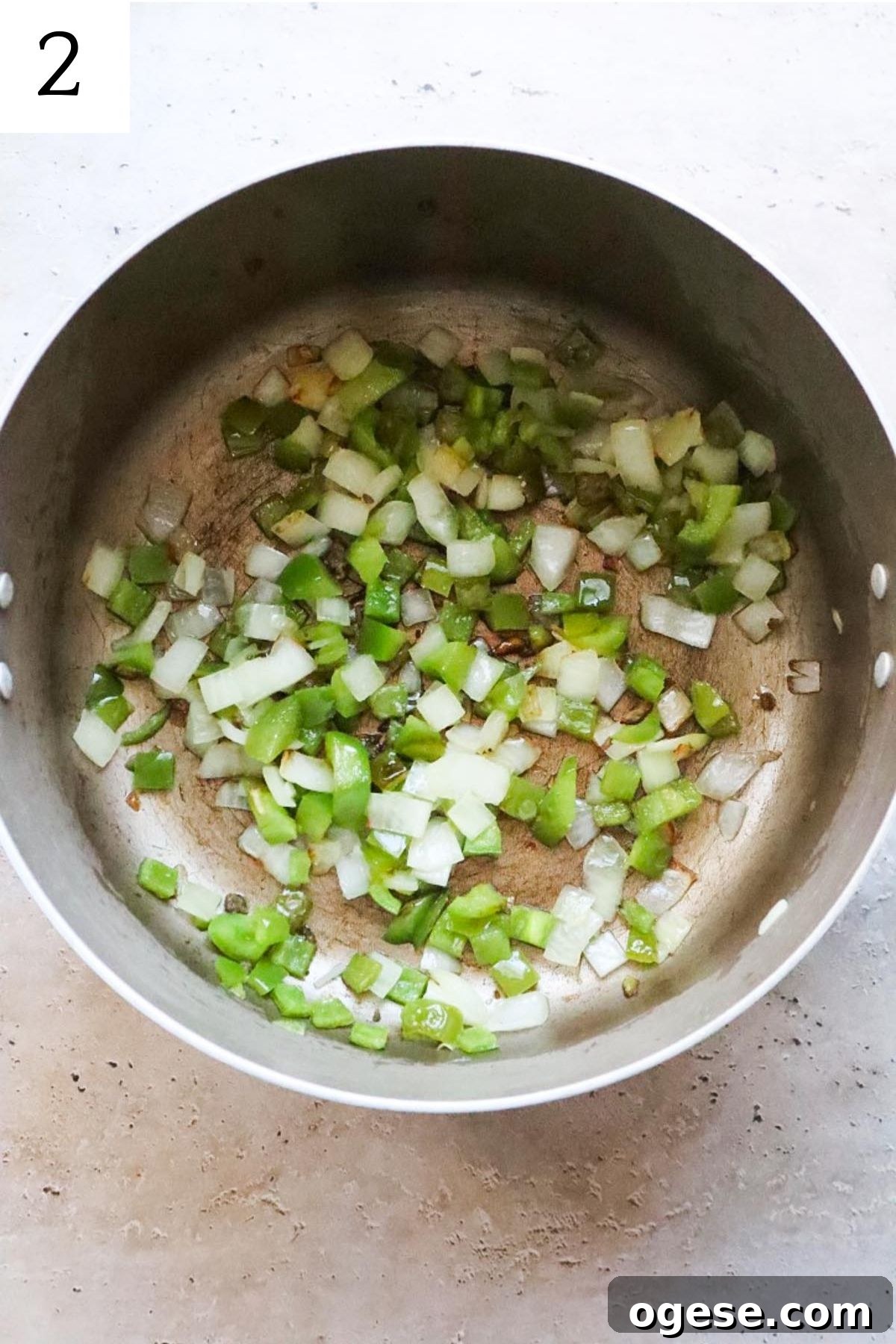 pot with cooked onion and green bell peppers.