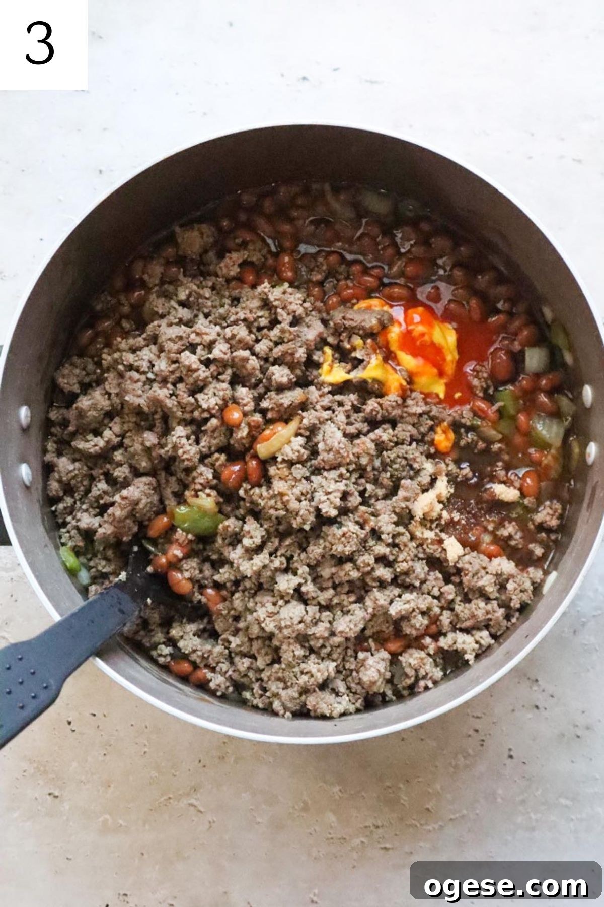 pot with ground beef baked beans and seasonings.
