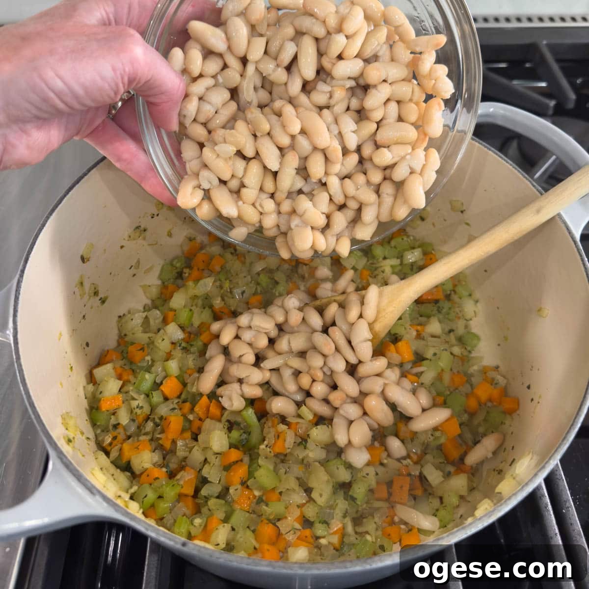 Tuscan White Bean Soup Recipe with Garlic and Kale 5 Adding white beans to a pot making a soup.