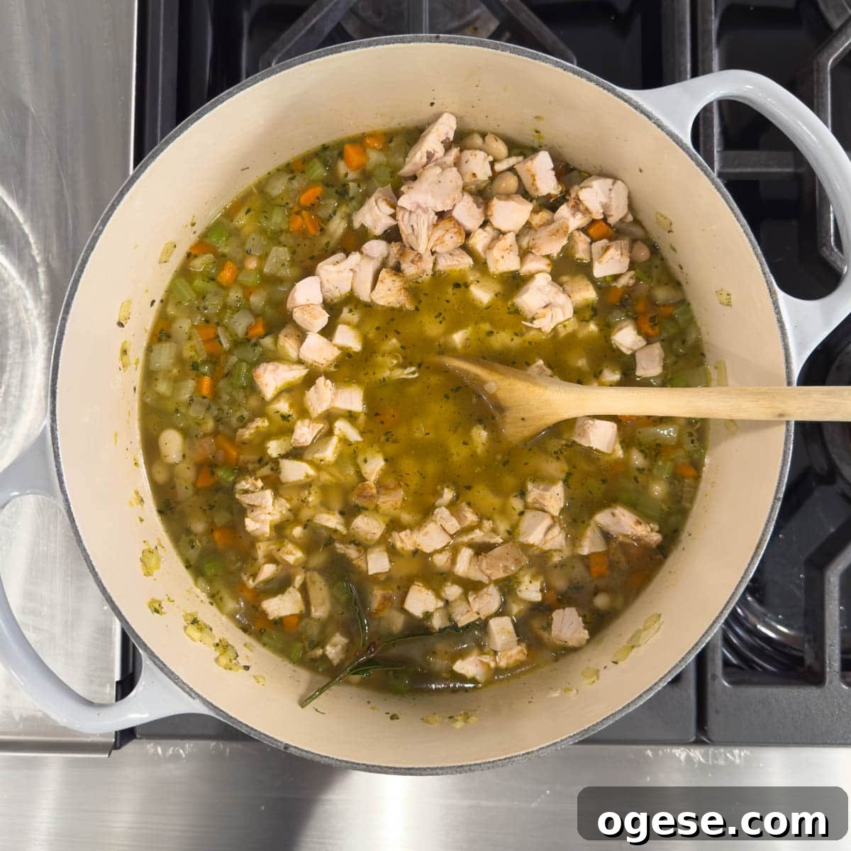 Tuscan White Bean Soup Recipe with Garlic and Kale 7 Adding chopped chicken to a pot for white bean soup.