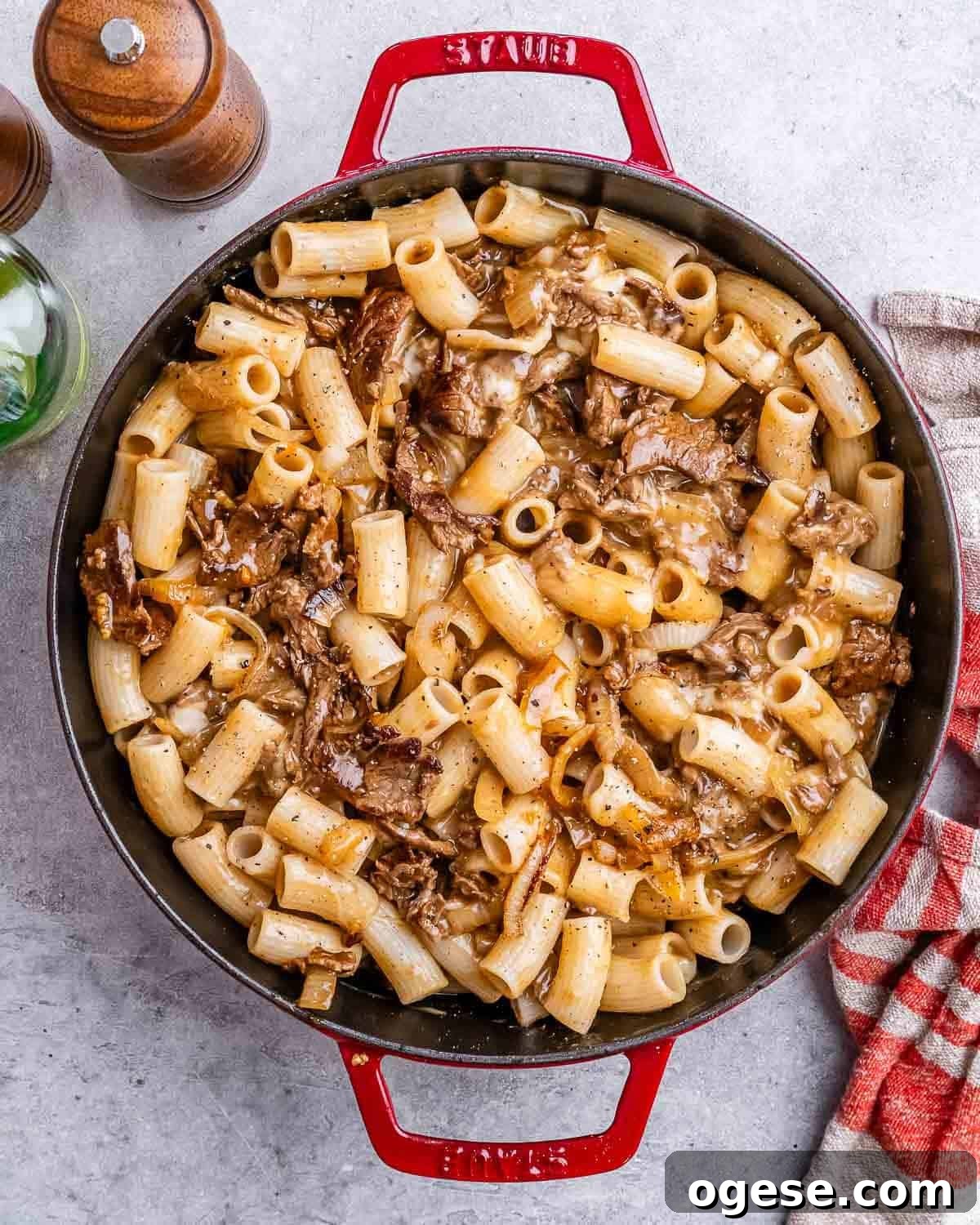 Creamy Philly Cheesesteak Pasta with Peppers & Onions 7 a red skillet with cheesy pasta and steak bites.