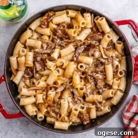 Creamy Philly Cheesesteak Pasta with Peppers & Onions 8 pasta with steak bites in a red skillet.